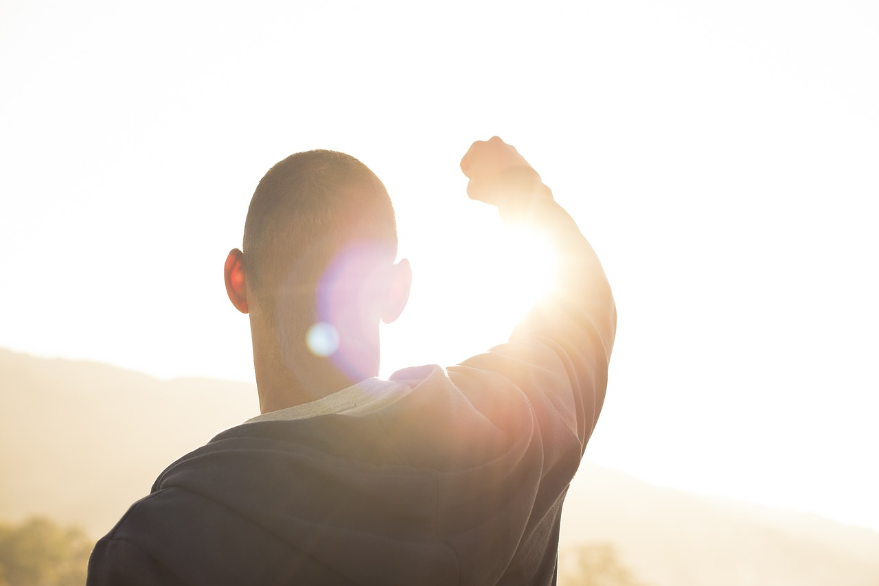 Homme point levé face soleil